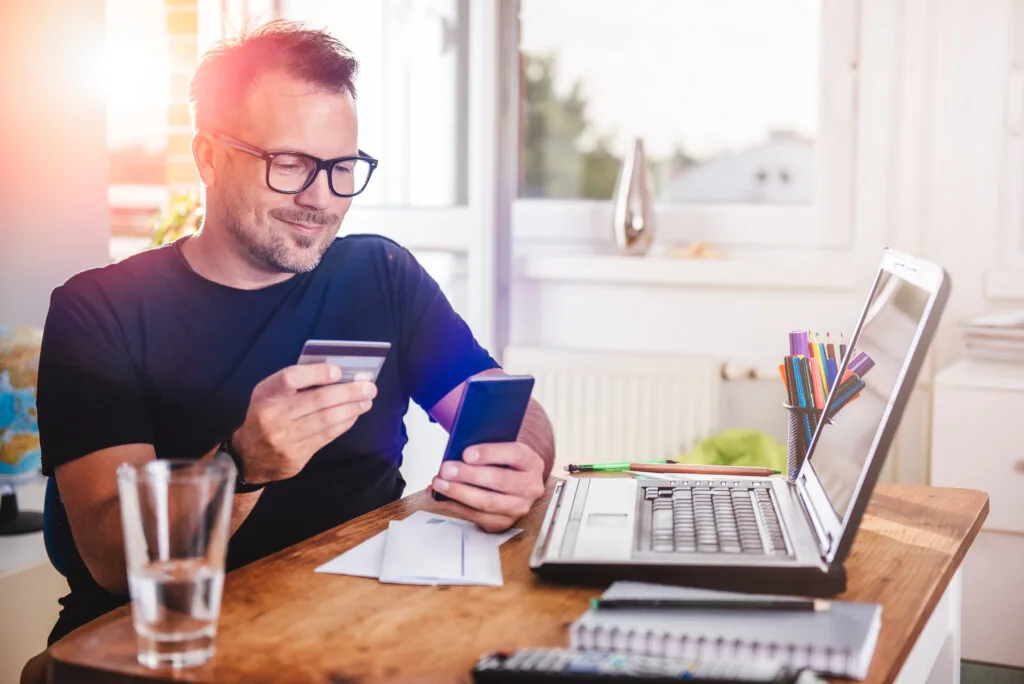 Happy customer holding credit card to pay online for junk removal services in Raleigh